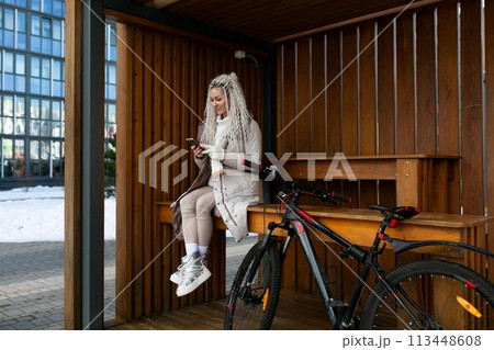 Woman Sitting on Bench Next to Bike Woman Sitting on Bench Next to Bike 113448608