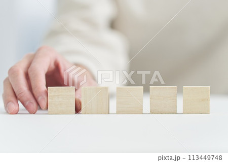 無垢の木のブロックを持つ手元 113449748