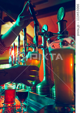 Beer culture. Bartender's hands pouring lager foamy beer from the taps with precision and care in mugs 113453066