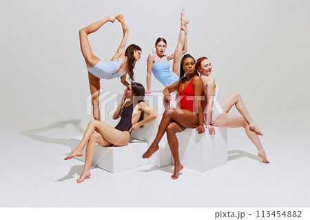 Creative portrait of young, beautiful woman in swimsuits in balanced poses on cubes against white studio background. Creative portrait of young, beautiful woman in swimsuits in balanced poses on cubes against white studio background. 113454882