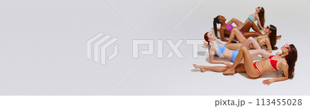Banner. Diverse women in colorful bikinis lounging in synchronized as on sandy beach against white studio background. Banner. Diverse women in colorful bikinis lounging in synchronized as on sandy beach against white studio background. 113455028