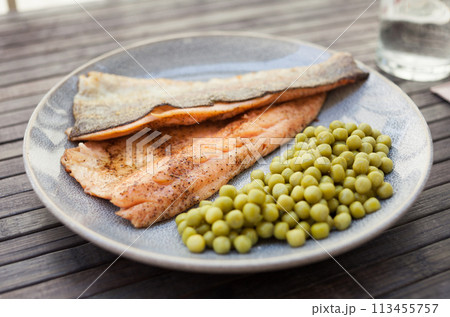 Top view of baked trout fillet served on plate with peas closeup 113455757