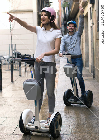 Young couple guy and girl walking on segway in streets of european city 113455760