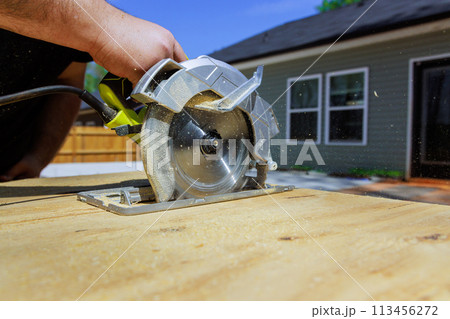 Using handsaw, carpenter trims plywood boards Using handsaw, carpenter trims plywood boards 113456272