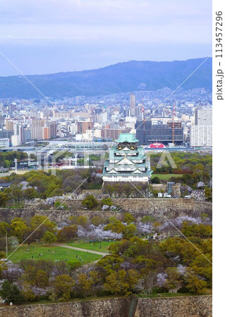 空から眺める大阪城鳥瞰図　桜の季節　生駒山系　春の青空に映える満開の桜 113457296