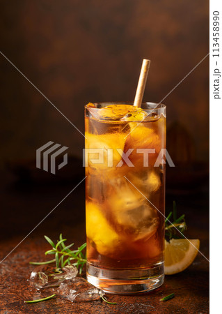 Iced tea or cocktail with ice, rosemary and lemon slices on the old brown table. 113458990