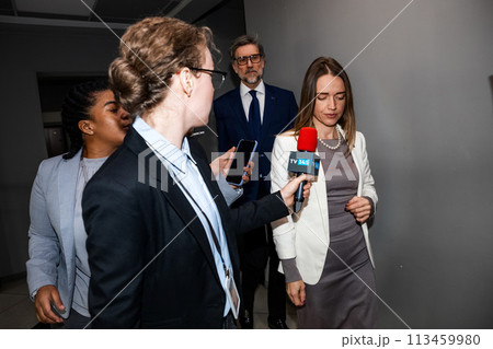 Positive female EU consul answers press questions in government building corridor 113459980