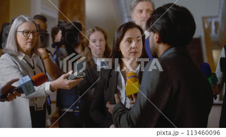 Female diplomat surrounded by crowd of journalists 113460096