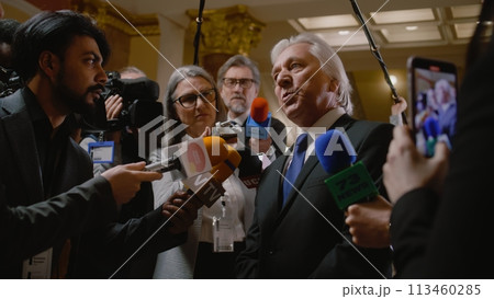 Senior diplomat surrounded by crowd of journalists 113460285