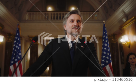 Confident US minister or congressman smiles, poses for cameras after political speech Confident US minister or congressman smiles, poses for cameras after political speech 113460510