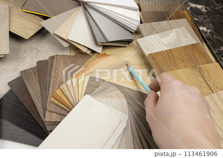 A woman designer shows with a pencil that she is holding in her hand, what is the best choice for the design of your project. The concept of design and selection of materials for the manufacture of A woman designer shows with a pencil that she is holding in her hand, what is the best choice for the design of your project. The concept of design and selection of materials for the manufacture of 113461906
