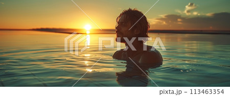 Woman standing in liquid horizon with colorful sky at sunset in ocean Woman standing in liquid horizon with colorful sky at sunset in ocean 113463354