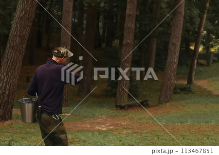 Forester collecting samples in the forest, holding a bucket, showcasing environmental conservation efforts and sustainable forestry practices. Environmental activist working in the forest 113467851