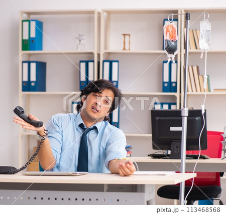 Young male employee in blood transfusion concept 113468568