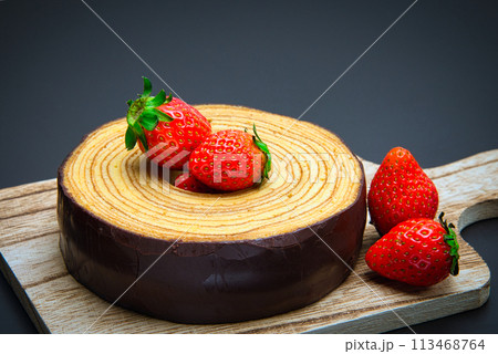 チョコレートでコーティングされた美味しそうなバウムクーヘンにフレッシュなイチゴを添えて チョコレートでコーティングされた美味しそうなバウムクーヘンにフレッシュなイチゴを添えて 113468764
