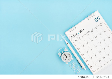 May 2024, Monthly desk calendar for 2024 year and alarm clock with paper clips on blue background. 113469693