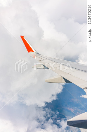 View from the airplane window at a beautiful cloudy sky and the airplane wing View from the airplane window at a beautiful cloudy sky and the airplane wing 113470216