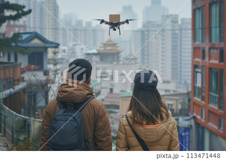 Two people are standing on a sidewalk, looking up at a drone flying overhead. logistic concept 113471448