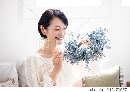 ユーカリのリースを持って微笑んでいるミドル女性 113471677