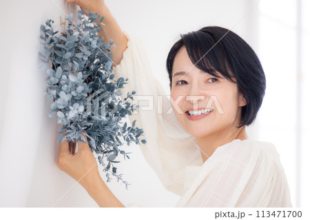 ユーカリのリースを持って微笑んでいるミドル女性 113471700