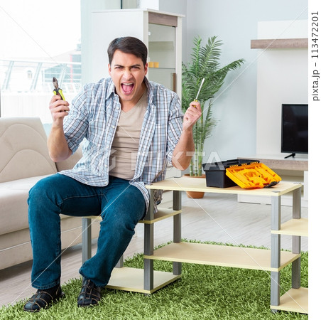 Man assembling furniture at home Man assembling furniture at home 113472201
