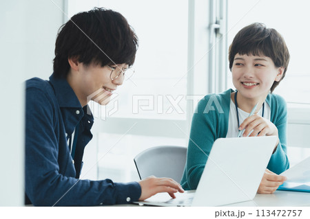 パソコンで仕事をする若い男女 113472757