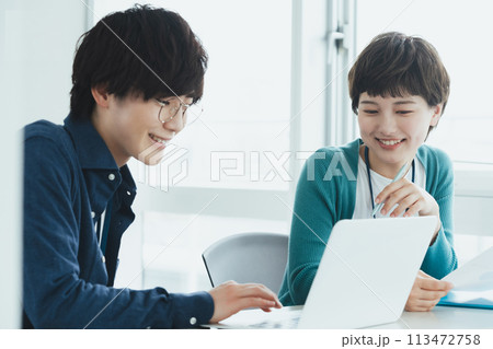 パソコンで仕事をする若い男女 パソコンで仕事をする若い男女 113472758