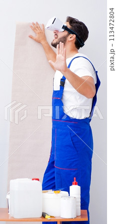 Man with VR glasses gluing wallpaper Man with VR glasses gluing wallpaper 113472804