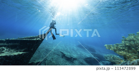 Freediver Sitting on Shipwreck in Shallow Sea With Sea Grass. Freediver Sitting on Shipwreck in Shallow Sea With Sea Grass. 113472899