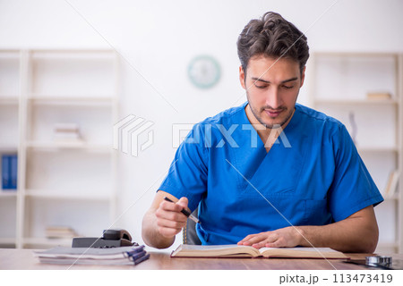 Young male doctor student reading book in the clinic 113473419