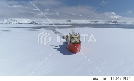 Icebreaker vessel navigating Antarctic waters - breaks through pack ice on its way. Aerial view. Featuring red color Laurence M. Gould Research Boat slicing through the Southern Ocean's ice expanse 113473994