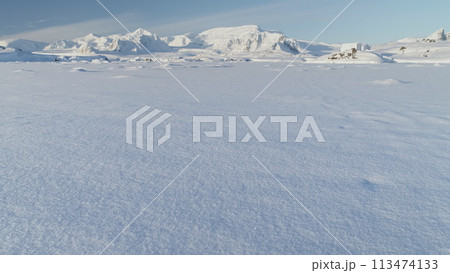 Panorama of scientific base in Infinitely, Infinitely polar snowy Antarctica desert. South Pole frost surface. Snow covered mountains on horizon. Aerial view flight. Ice Landscape. Winter frozen Panorama of scientific base in Infinitely, Infinitely polar snowy Antarctica desert. South Pole frost surface. Snow covered mountains on horizon. Aerial view flight. Ice Landscape. Winter frozen 113474133