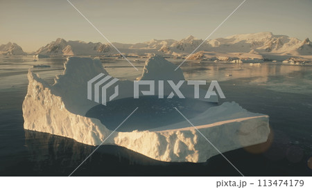 Iceberg pool. Antarctica aerial view drone flight. Slow motion flying over the large iceberg with water pool in the polar ocean next to the snow covered mountains of Antarctic continent. Iceberg pool. Antarctica aerial view drone flight. Slow motion flying over the large iceberg with water pool in the polar ocean next to the snow covered mountains of Antarctic continent. 113474179