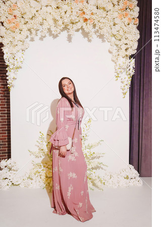 woman in a pink dress with a badge on the zone for taking photos at the party. woman in a pink dress with a badge on the zone for taking photos at the party. 113474580