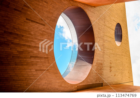 Futuristic geometric abstraction perspective in the form of a wall with rectangular tiles and two holes in the wall, one of them can see a blue sky with clouds. Horizontal photo Futuristic geometric abstraction perspective in the form of a wall with rectangular tiles and two holes in the wall, one of them can see a blue sky with clouds. Horizontal photo 113474769