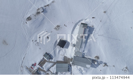 Aerial drone view flight. Vernadsky Base, ocean, mountains. Fast. The station settlement on the Antarctica continent surrounded snow covered mountains and ice ocean. Harsh conditions. 113474944