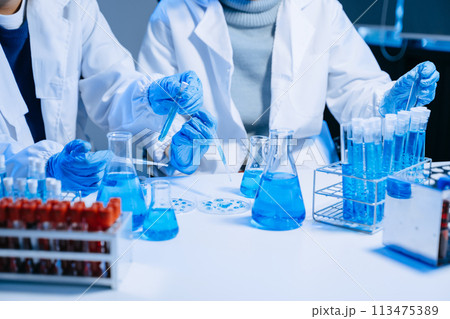Two Scientist mixing chemical liquids in the chemistry lab. Researcher working in the chemical laboratory 113475389