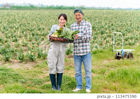 農作物をかかえて笑顔を見せる若い女性とベテラン農夫 農作物をかかえて笑顔を見せる若い女性とベテラン農夫 113475390