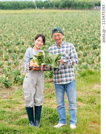 農作物をかかえて笑顔を見せる若い女性とベテラン農夫 113475393