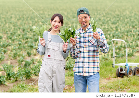 農作物を手にして笑顔を見せる若い女性と中年男性 113475397