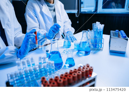 Two Scientist mixing chemical liquids in the chemistry lab. Researcher working in the chemical laboratory Two Scientist mixing chemical liquids in the chemistry lab. Researcher working in the chemical laboratory 113475420
