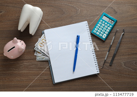 Tooth, dental instruments, piggy bank and cash, notepad and calculator on wooden background, top view Tooth, dental instruments, piggy bank and cash, notepad and calculator on wooden background, top view 113477719