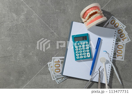 Jaw and dental instruments, calculator, cash and notepad on gray background, space for text 113477731