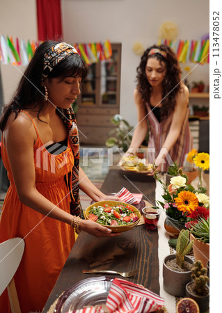 Putting homemade salad on festive table Putting homemade salad on festive table 113478052