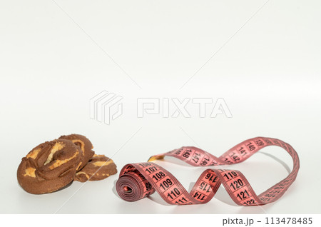 Chocolate marble cookie slices with pink measuring tape on white background. 113478485
