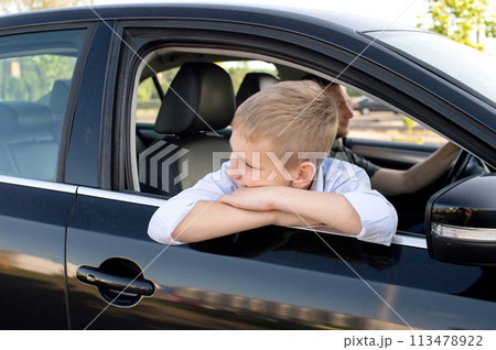 The cute boy climbed out of the car window and looks away. Go with Dad in the car The cute boy climbed out of the car window and looks away. Go with Dad in the car 113478922
