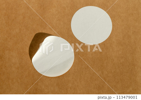 Round white stickers on brown paper background with natural sunlight. Round white stickers on brown paper background with natural sunlight. 113479001