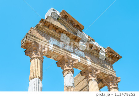 The ruins of a beautiful white Roman building are built into reconstructed brick columns and the front of the portico against the blue sky. Horizontal photo 113479252
