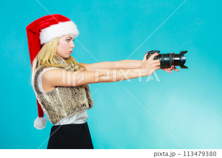 Photographer girl in santa claus hat shooting images Photographer girl in santa claus hat shooting images 113479380