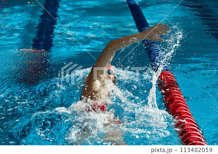 Dynamic image of young man, swimmer in cap and goggles in action, motion, swimming freestyle stroke in pool. 113482059